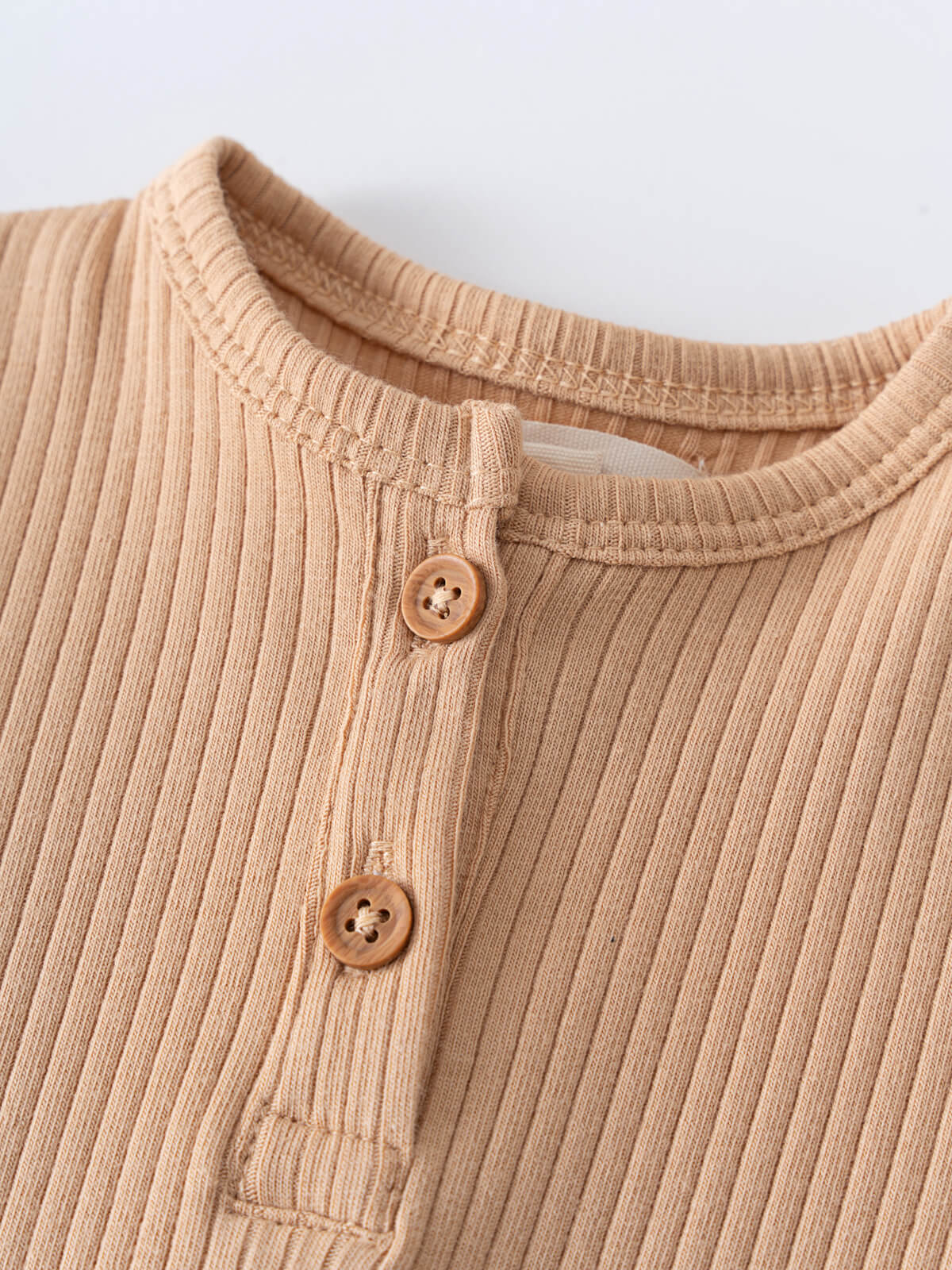 Close-up of beige ribbed fabric with wooden buttons near neckline Henley Short Sleeve Bodysuit - Sand Baby boy