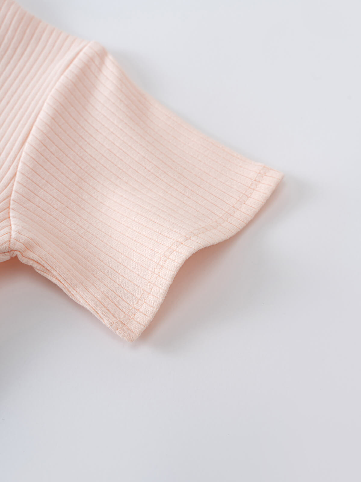 Close-up of a pale pink ribbed knit fabric with textured sleeve detail Henley Short Sleeve Bodysuit Shell Pink Baby girl