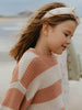 Young girl wearing a striped sweater with a blurred outdoor background