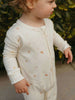 Child wearing a light-colored onesie with subtle patterns outdoors.