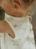 Close-up of a child wearing a sleeveless top with fruit patterns.