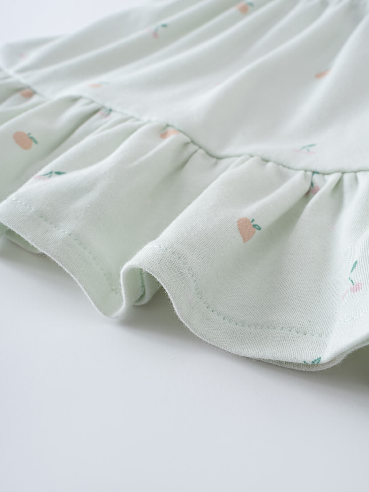 Close-up of light green fabric with small peach and fruit print pattern Jersey Skirt - Summer Fruits Girls