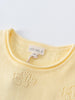 Close-up of a pale yellow knit garment showing neckline and label detail Knit Tee - Sun Soaked Girls