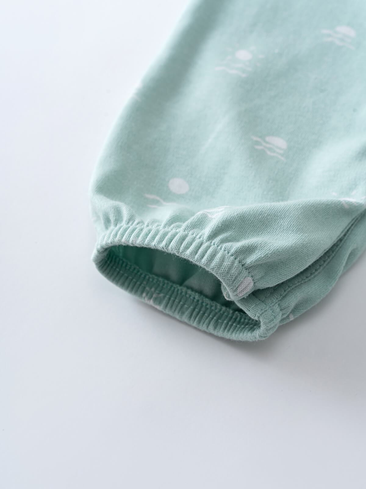 Close-up of light blue fabric sleeve cuff with elastic gathering and white polka dots Leo Romper - Summer Time Baby boy