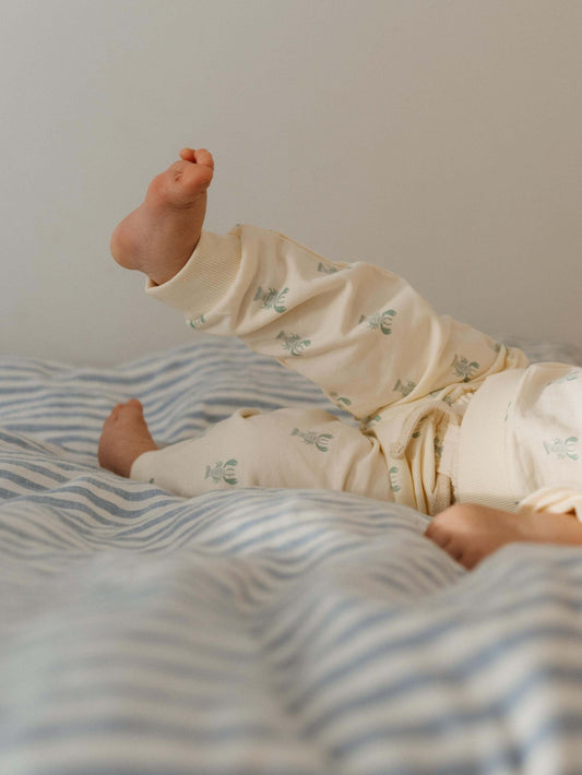 Baby playing with his feet on the bed.