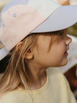 Child wearing a two-tone cap with a blurred background