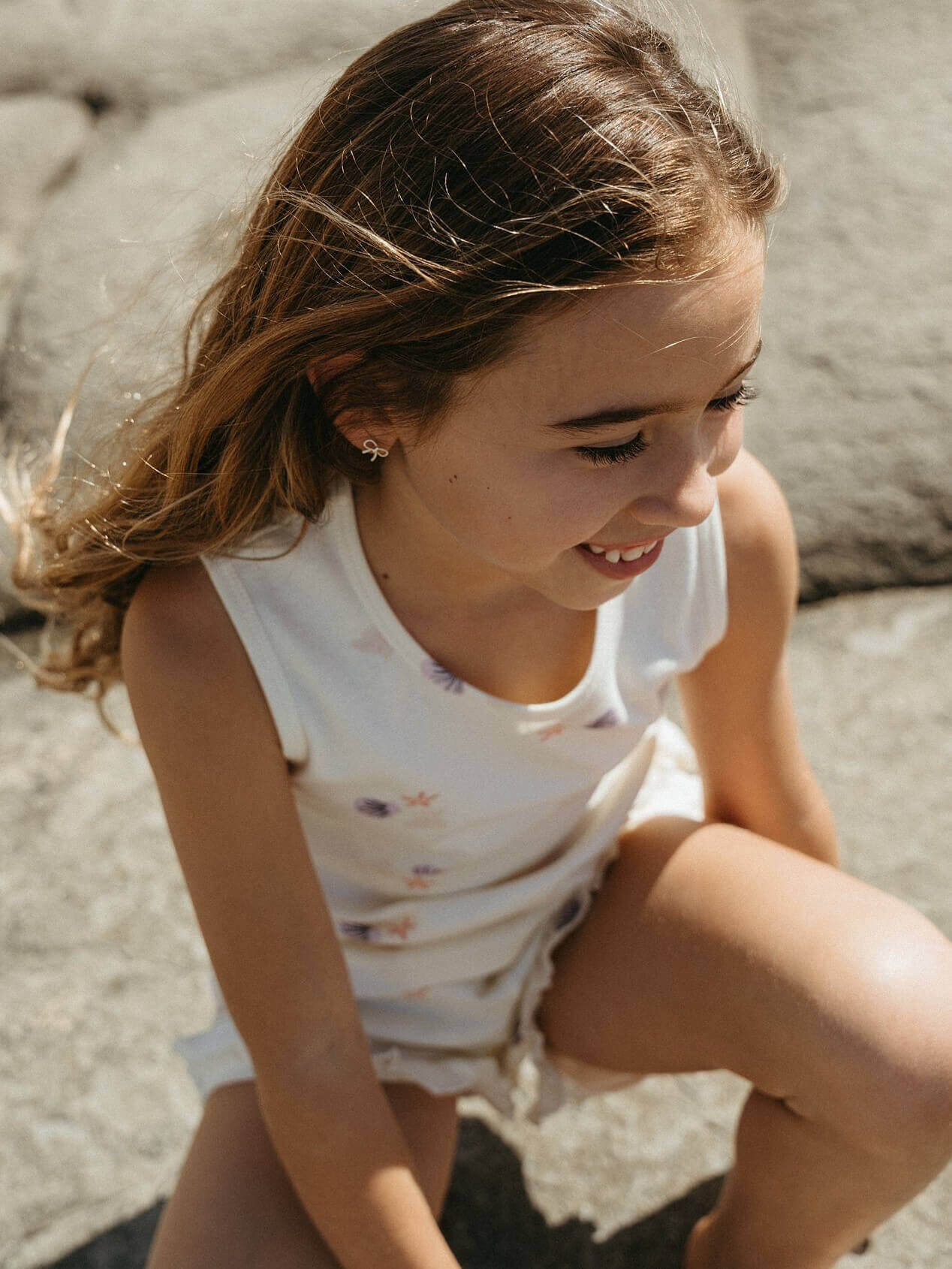 Young girl sitting on a rock with a blurred natural background