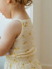 Child wearing a sleeveless top with lemon pattern against a neutral background