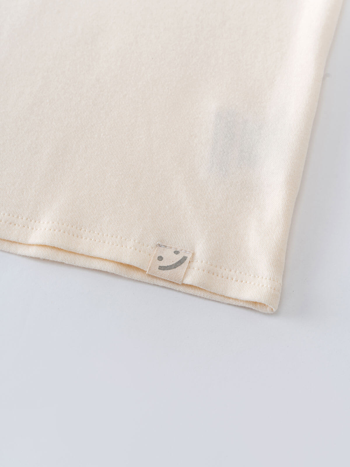 Close-up of cream fabric corner with small smiley face tag detail Feature Print Short Sleeve Tee - Hiking Bear Boys