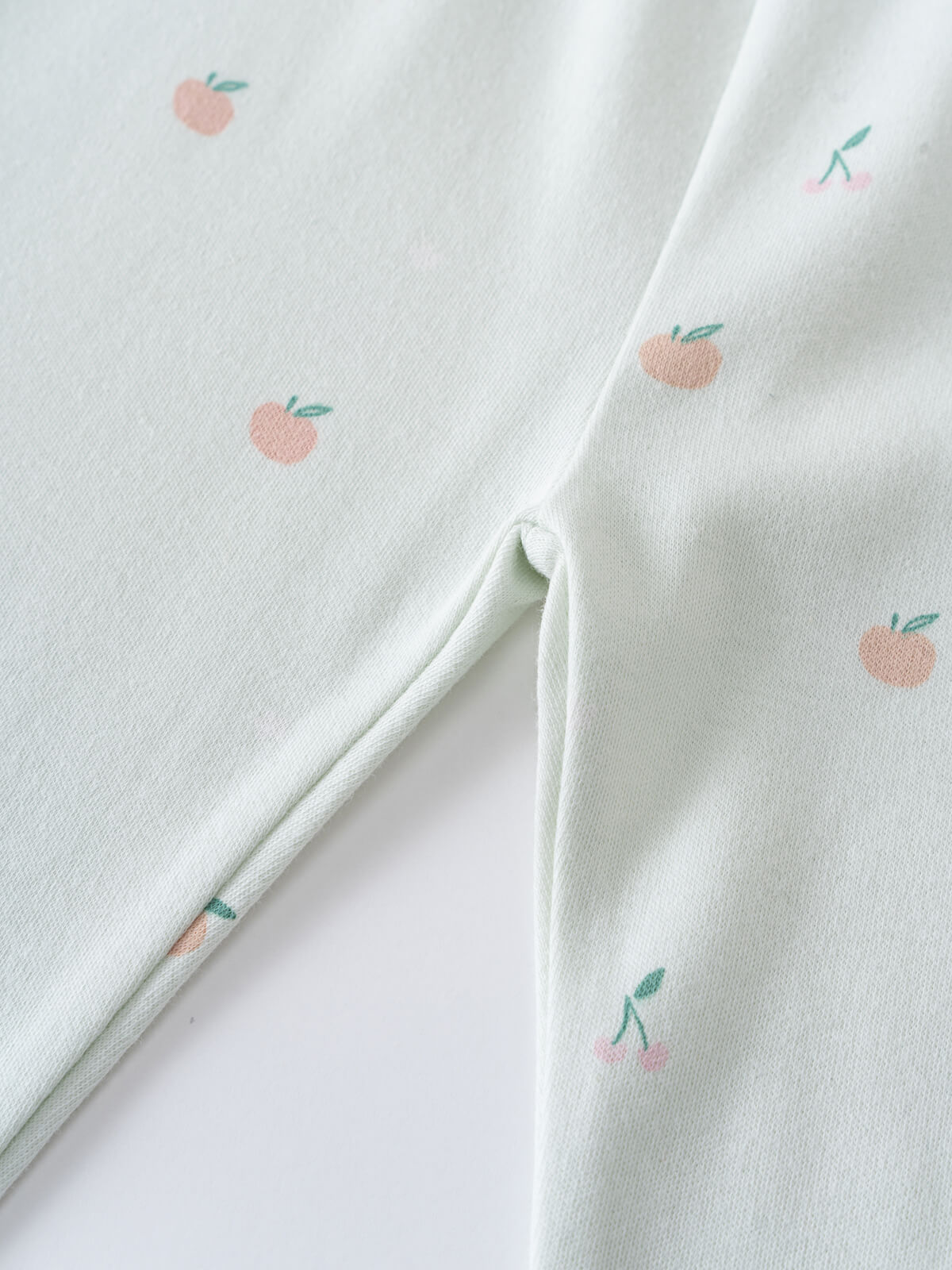 White fabric with small embroidered peach pattern, showing fold and texture Printed Leggings - Summer Fruits Girls