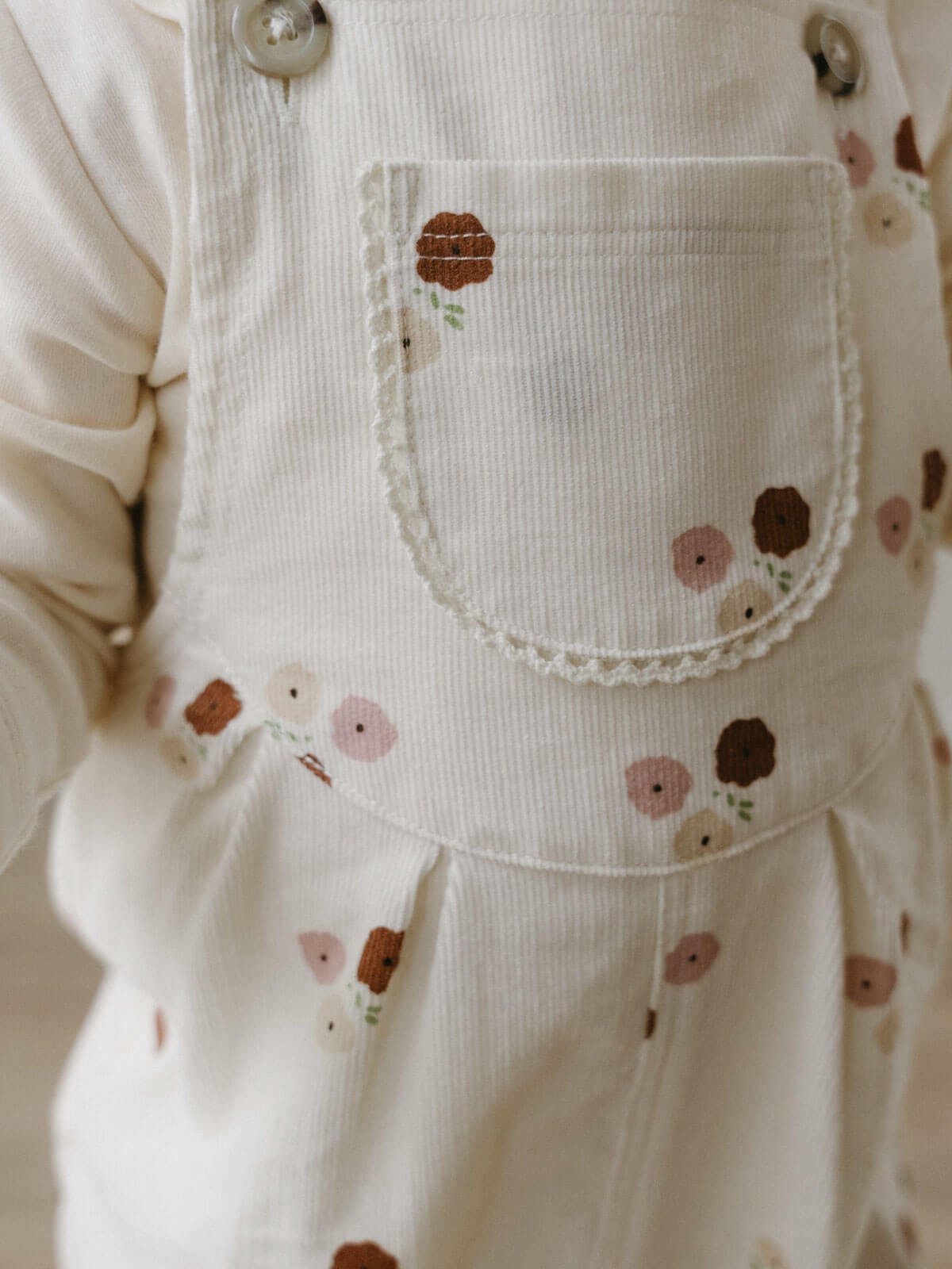 Close-up of cream corduroy overalls with floral embroidery on pocket Printed Overalls - Autumn Bouquet Ecru Baby girl