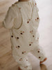 Baby wearing cream overalls with floral embroidery, sitting on beige surface Printed Overalls - Autumn Bouquet Ecru Baby girl