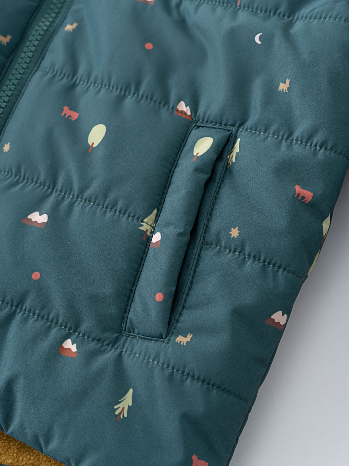 Close-up of teal quilted vest with trees, animals, and moon print Printed Puffer Vest Jacket - Mountain View Balsam Boys