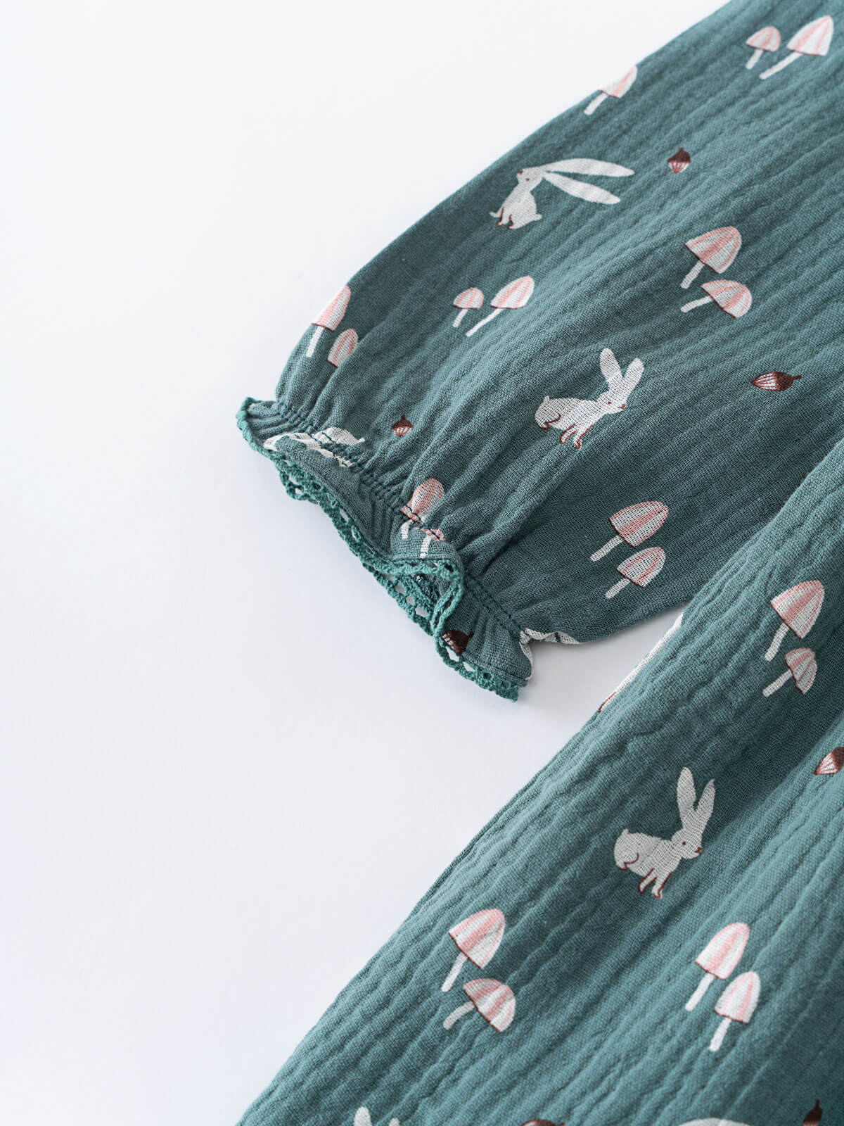 Green dress fabric with rabbit and mushroom pattern on a white background