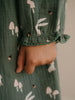 Hand holding a green fabric with mushroom and rabbit pattern