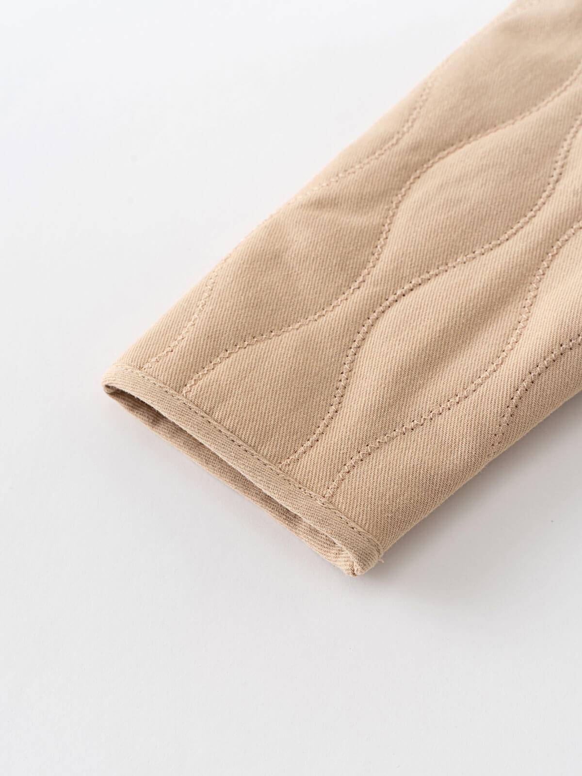 Close-up of beige fabric with a textured pattern on a white background Quilted Jacket - Clay Baby girl