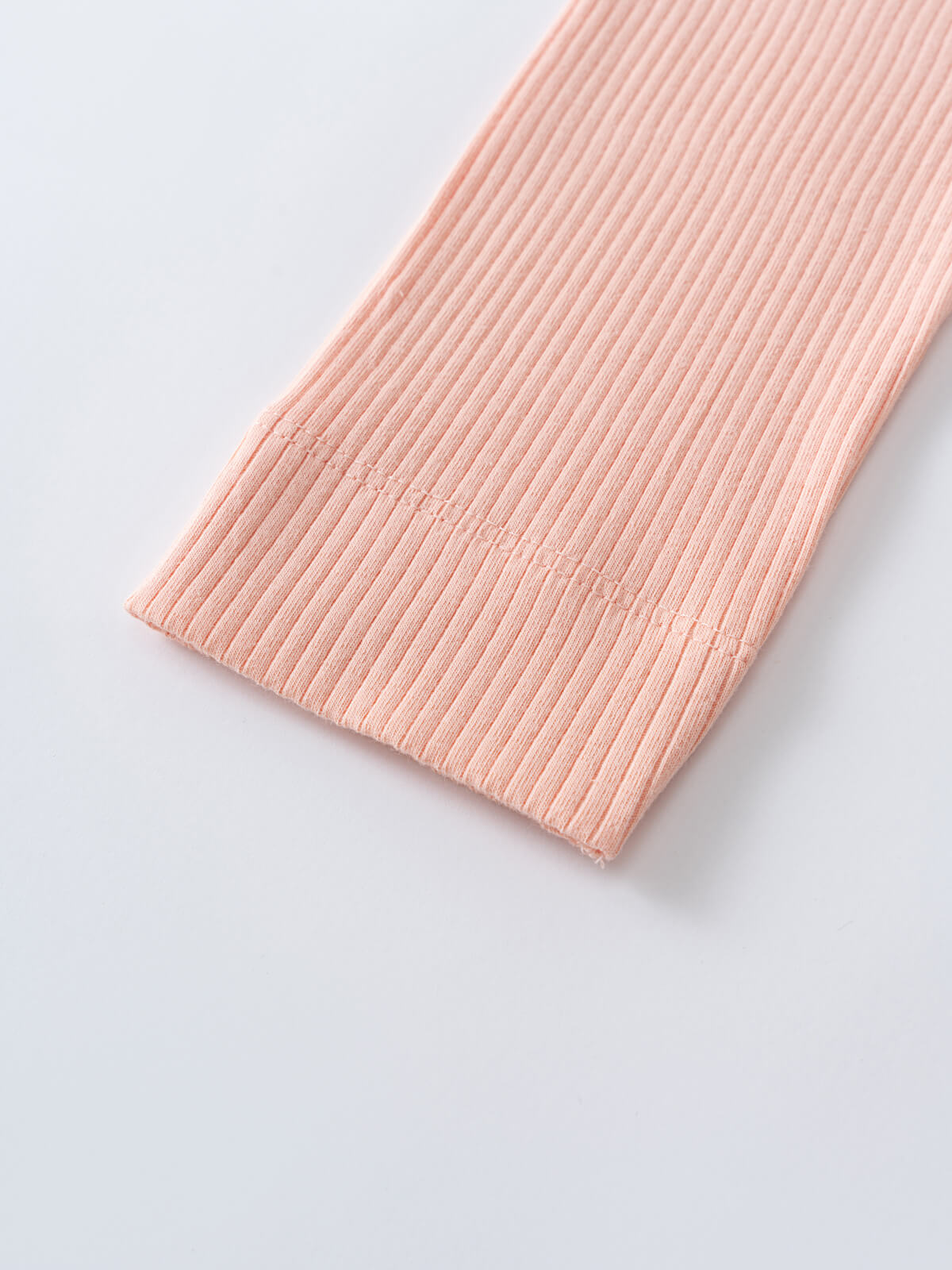 Close-up of ribbed peach fabric with a finished hemmed edge Ribbed Leggings - Toasted Peach Girls