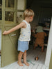 Child playing inside a wooden playhouse with another child in the background.