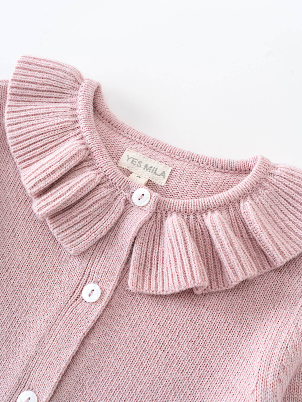 Close-up of a pink ribbed knit cardigan with ruffled collar and white buttons Ruffle Cardigan - Blush Girls