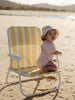 Baby girl wearing a soft pink bodysuit siting on a beach chair