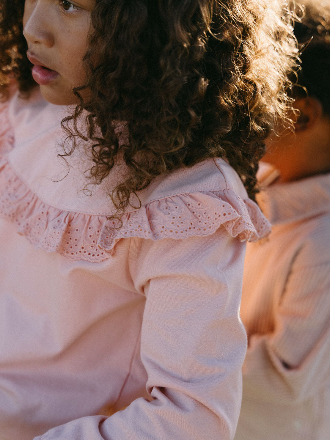 Young girl with curly hair wearing a pink eyelet ruffle collar top Ruffle Top - Mallow Girls