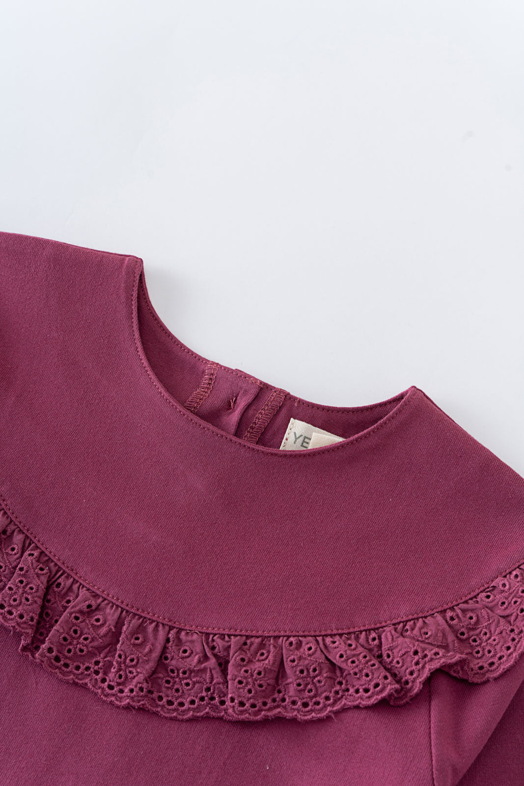 Close-up of a maroon blouse with lace trim on a white background Ruffle Top - Plum Jam Girls