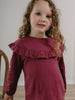 Young girl with curly hair wearing a plum-colored long-sleeved top with ruffled collar Ruffle Top - Plum Jam Girls