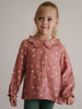 Young girl wearing a pink patterned button-up blouse with ruffled collar Ruffle Woven Blouse - Bird And Blossom Rosehip Girls