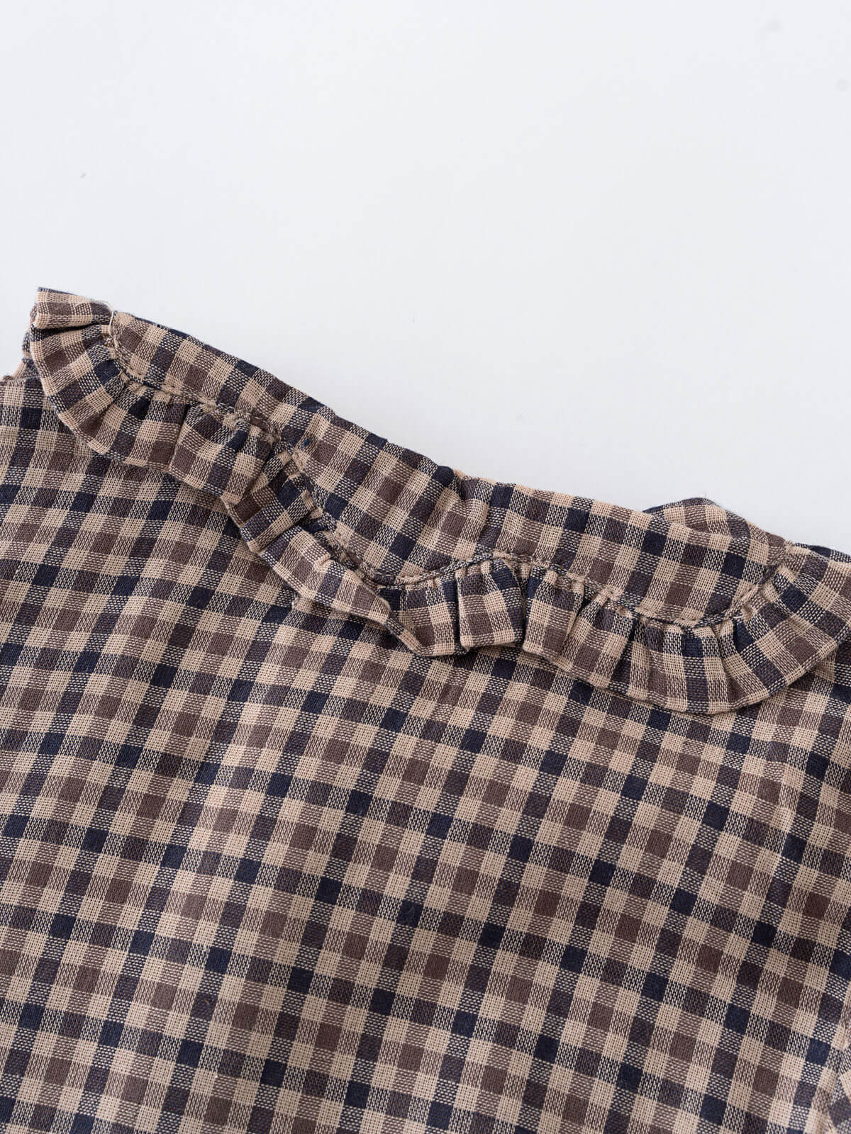 Close-up of a checkered fabric with ruffled trim on a white background Ruffle Woven Blouse - Muslin Cotton Check Girls