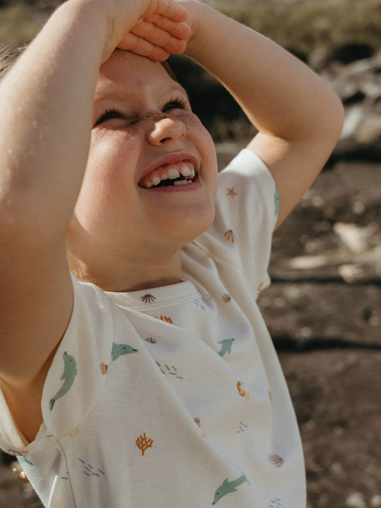 Child wearing a white shirt with nature-themed patterns outdoors