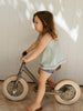 Child riding a balance bike indoors with a neutral background