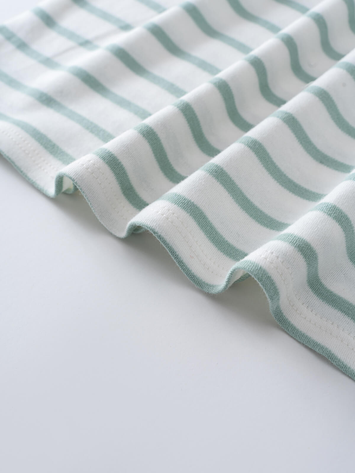 Close-up of white fabric with sage green curved stripes, shown folded Short Sleeve Dress - Harbour Stripe Girls