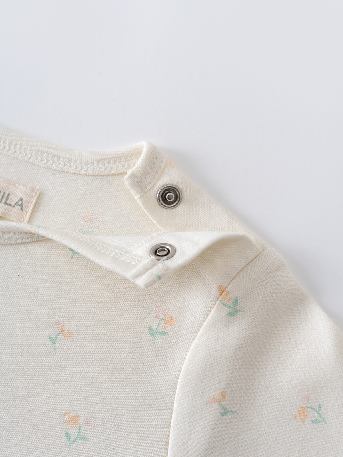 Close-up of cream colored baby bodysuit with floral print and metal snap buttons Long Sleeve Bodysuit - Spring Bloom Baby girl