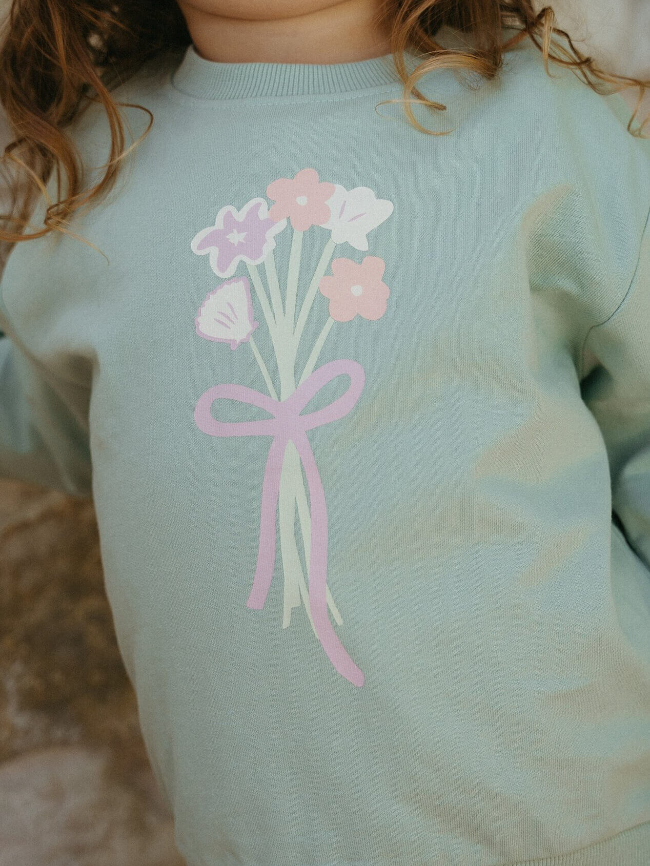Light blue sweatshirt with pink flowers and a bow design on a blurred background Sophie Sweatshirt - Posy Mint Girls