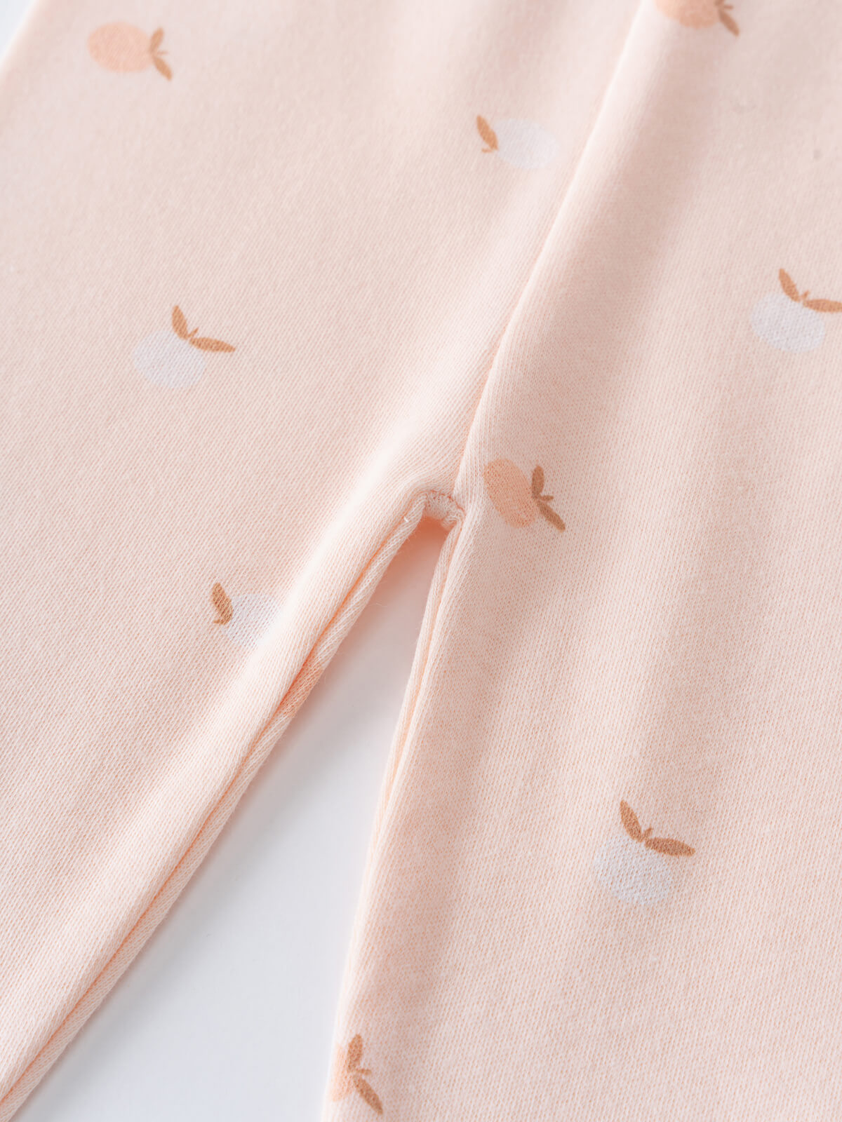 Close-up of pale pink fabric with small orange apple print pattern Stella Leggings - Apples Baby girl