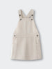 Cream-colored overall dress with crossed back straps and button details Twill Pinafore Dress - Salt Girls